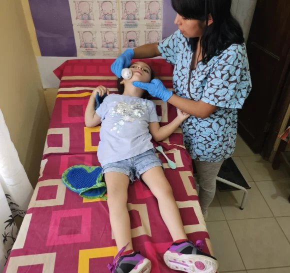 Durante una sesión de terapia, Laura Giovana masajea la cara de Tamara con un masajeador facial. © Y. Franco / HI